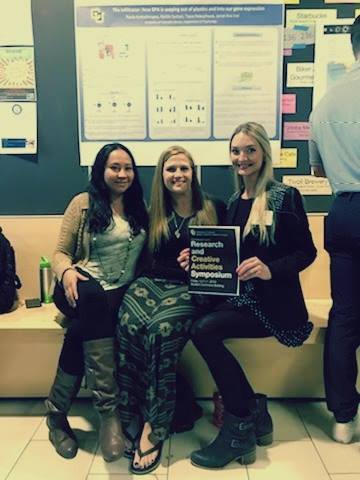 Image of Paula and research peers sitting in front of research board.